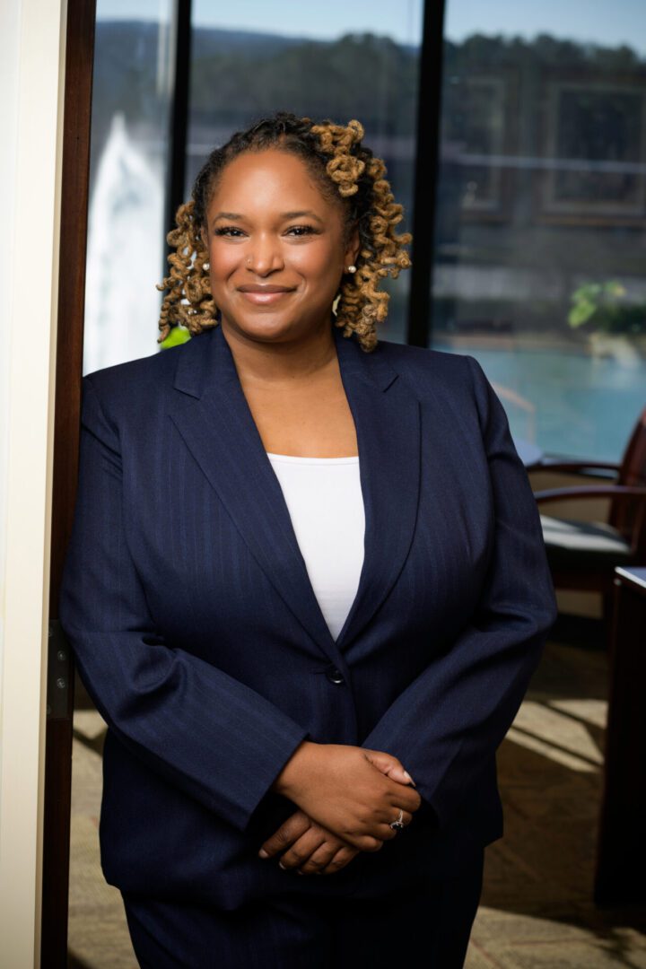 Confident woman in a navy blazer smiling indoors.