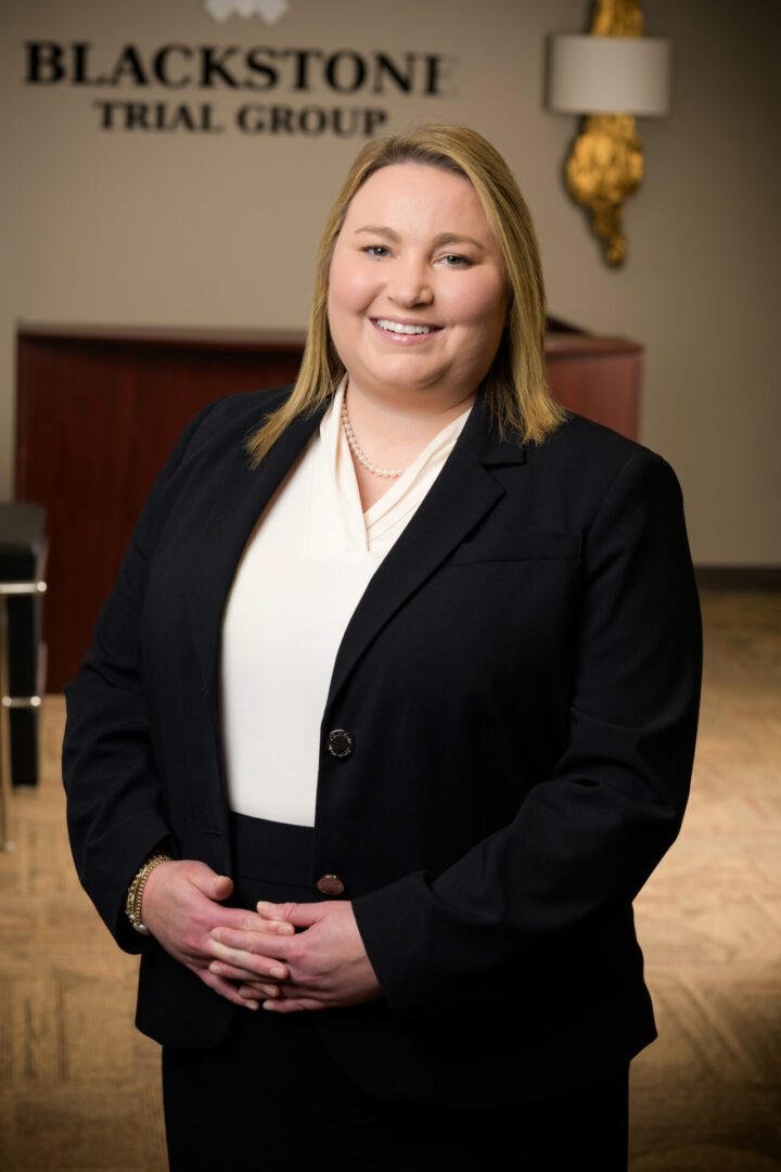 A confident woman in professional attire smiling warmly.