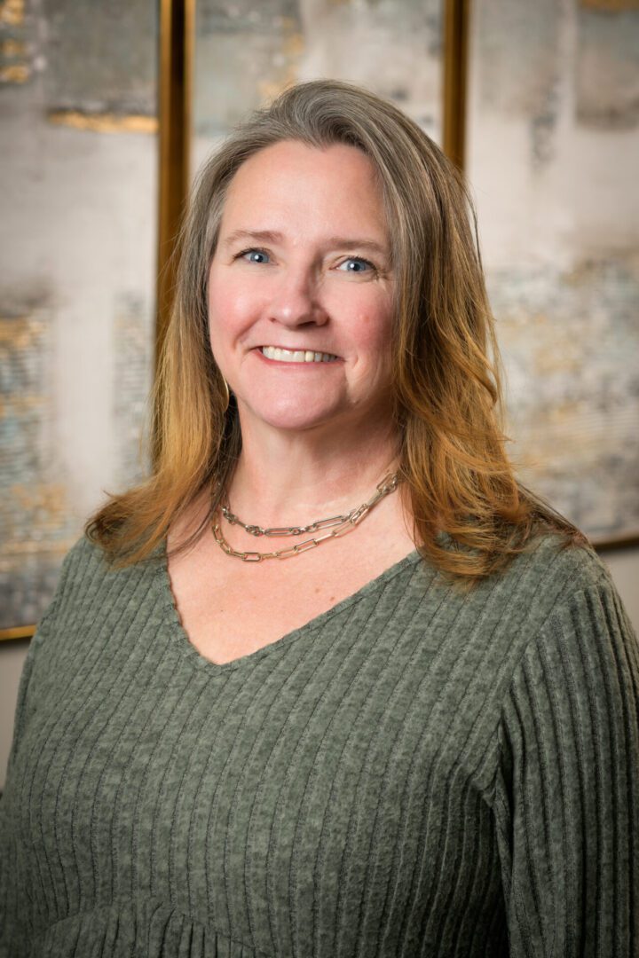 Smiling woman with shoulder-length hair wearing a green sweater.
