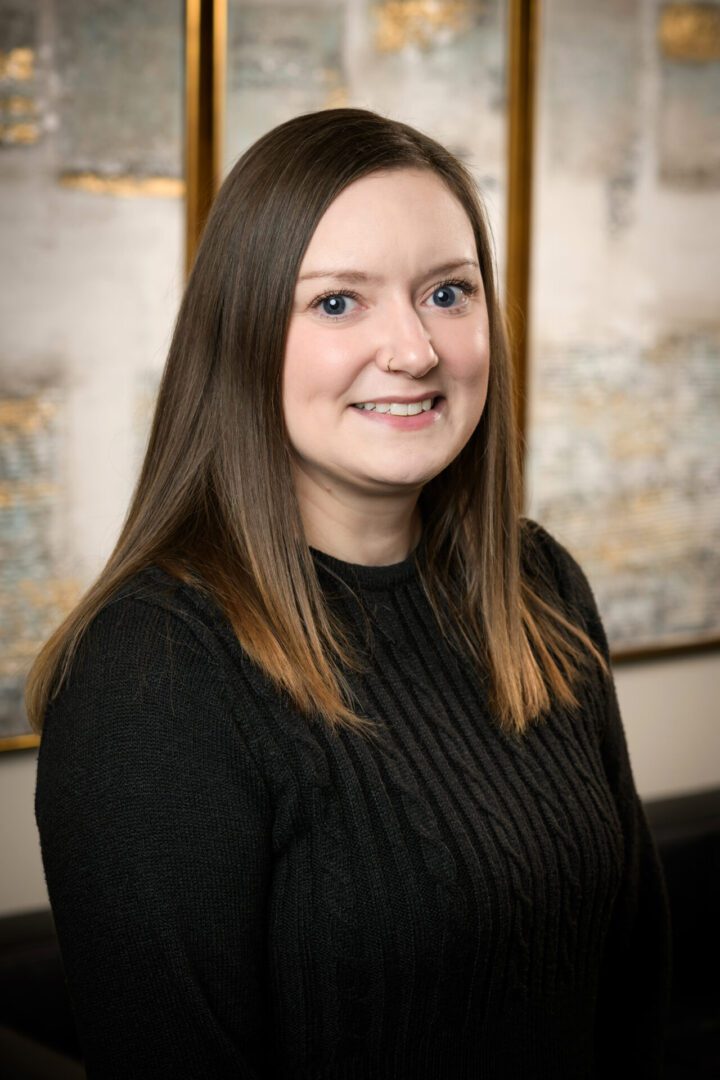 Professional woman smiling in a black sweater against a blurred background.