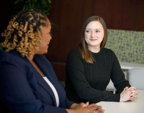 Two women engaged in a professional conversation at a meeting.