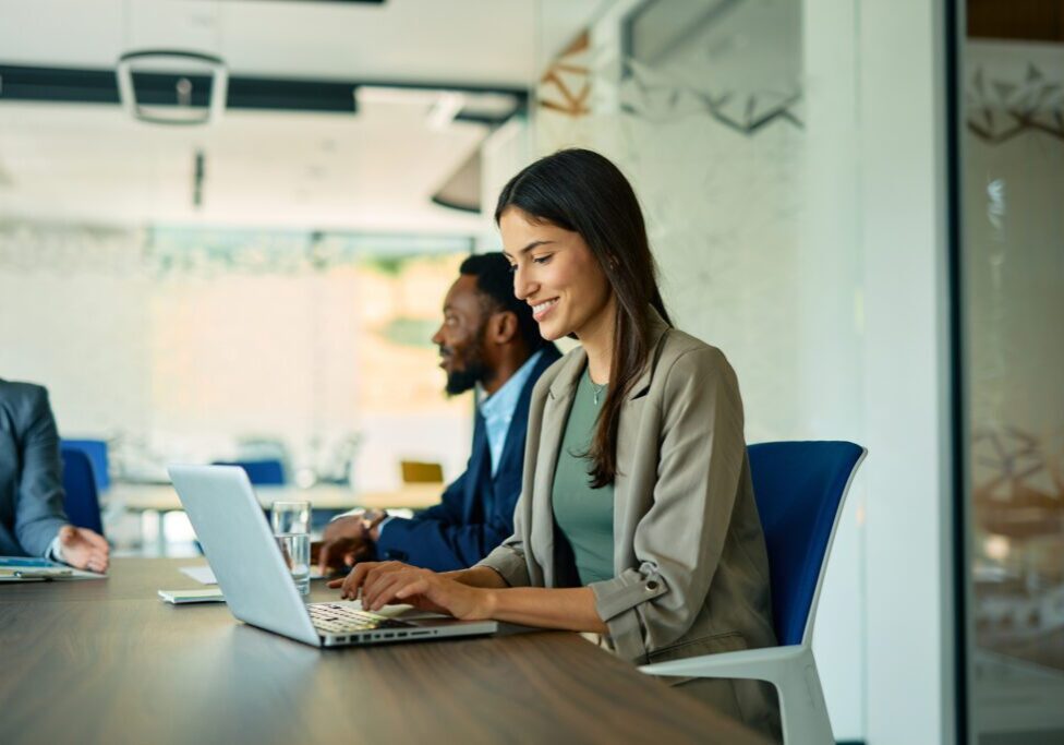 Woman working on laptop in office meeting.